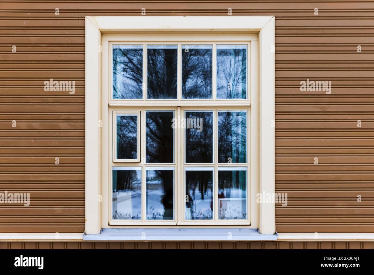 Fenster mit weißem Rahmen in beigefarbener Holzwand Stockfoto
