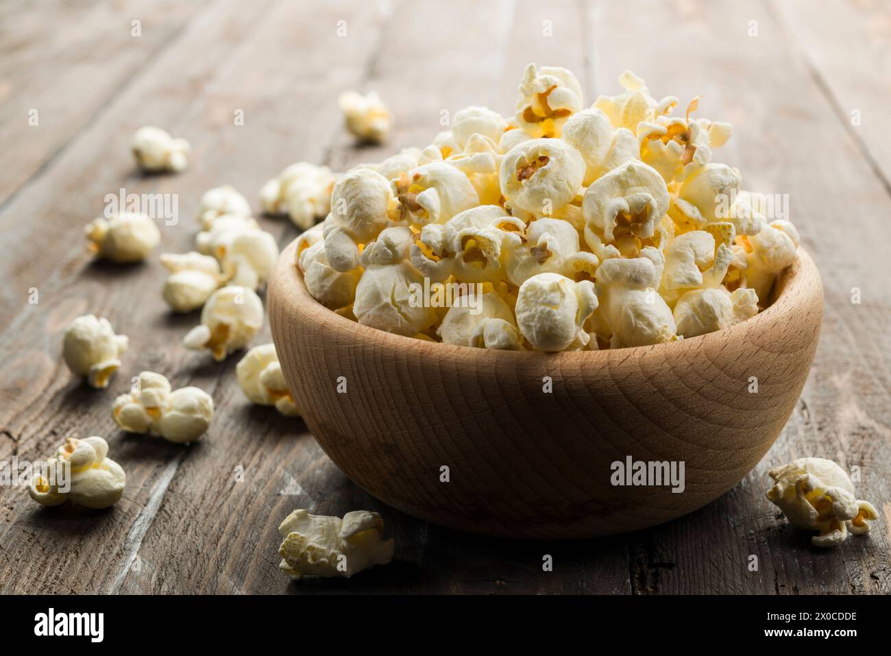 Holzschale mit gesalzenem Popcorn auf Holztisch. Stockfoto