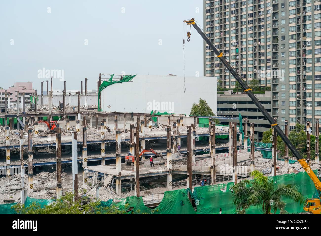 Abriss des Gebäudebodens für Etage, Arbeiter demontieren tragende Stützen von Pfählen, Minibagger. Baumaschine Kranwagen nahe Stockfoto