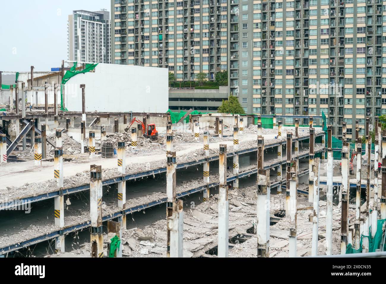 Abriss des Gebäudebodens für Etage, Arbeiter demontieren tragende Stützen von Pfählen, Minibagger. Stockfoto