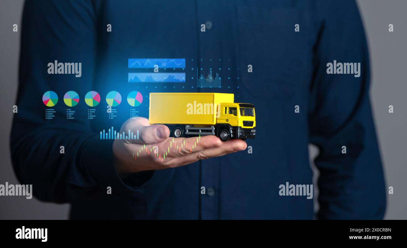 Geschäftsmann mit einem Truck und Wirtschaftstabellen. Logistikbranche. Transportoptimierung. Auswahl der Liefermethoden, effektive Anzahl der Fahrzeuge Stockfoto