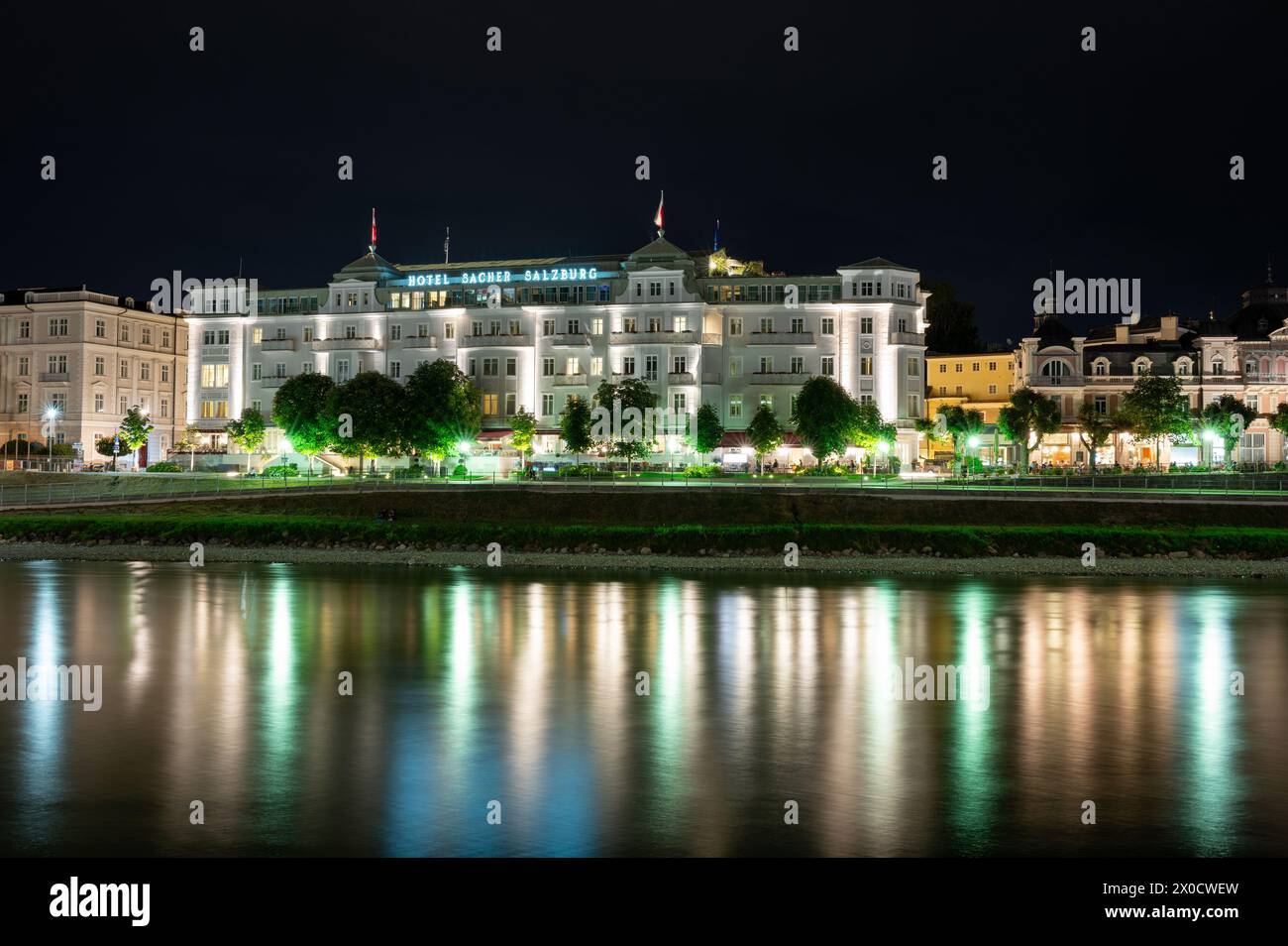 Salzburg, Österreich, 15. August 2022. Ikonisches Nachtbild des Luxushotels Sacher, das sich im Wasser der Salzach spiegelt. Kopierbereich. Stockfoto