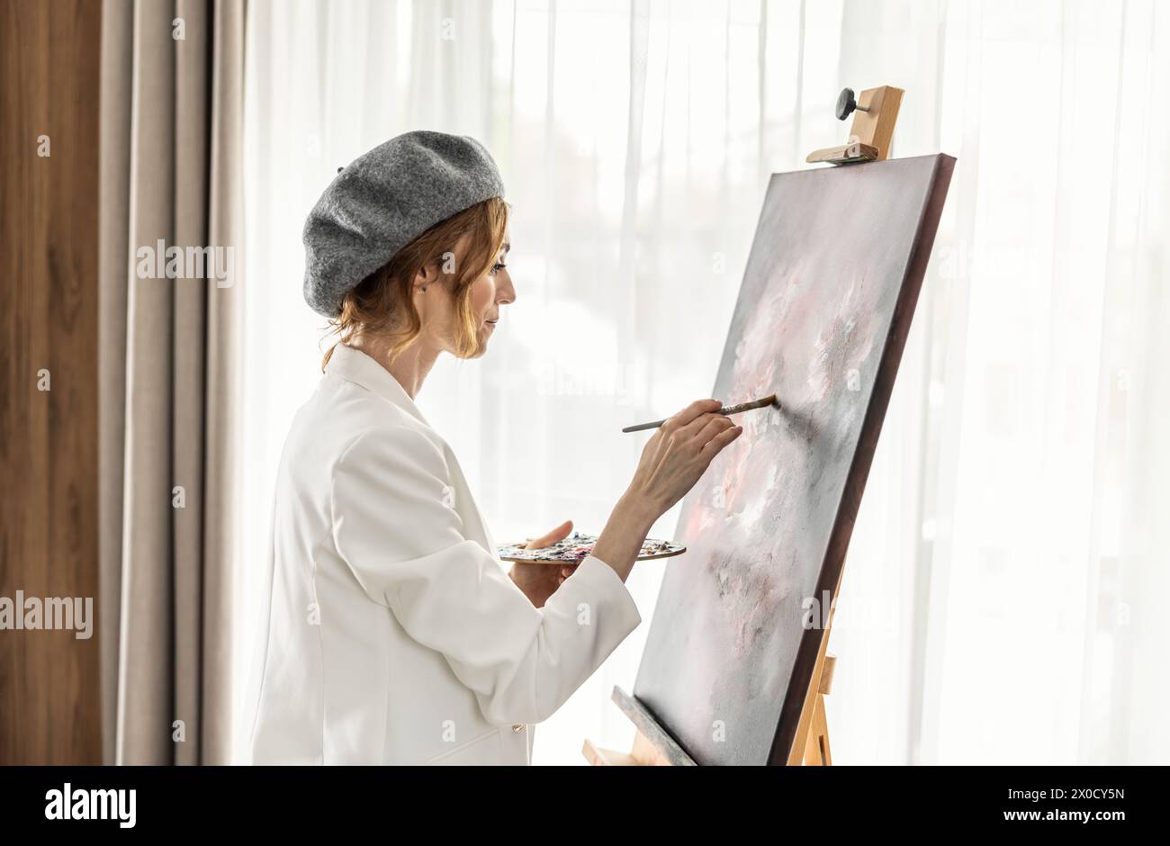 Schöne Malerin genießt beim Malen im Kunststudio zu Hause. Die Künstlerin arbeitet an abstrakter Acrylmalerei im Atelier. Stockfoto