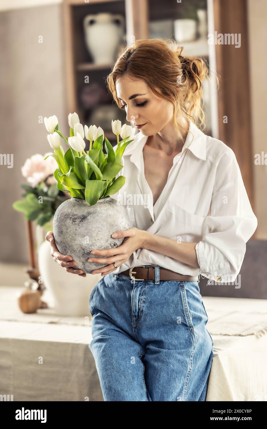 Die Hausfrau genießt einen Haufen Blumen und das Innere des Wohnzimmers. Glückliche Frau genießt Tulpenstrauß. Stockfoto