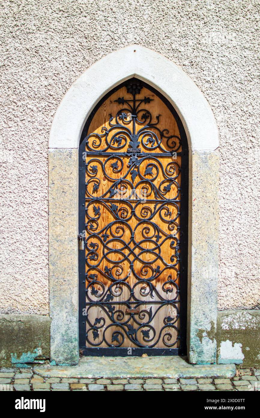 Eine kleine Holztür mit einem geschmiedeten Metallgitter in der Wand der Abtei. Stockfoto