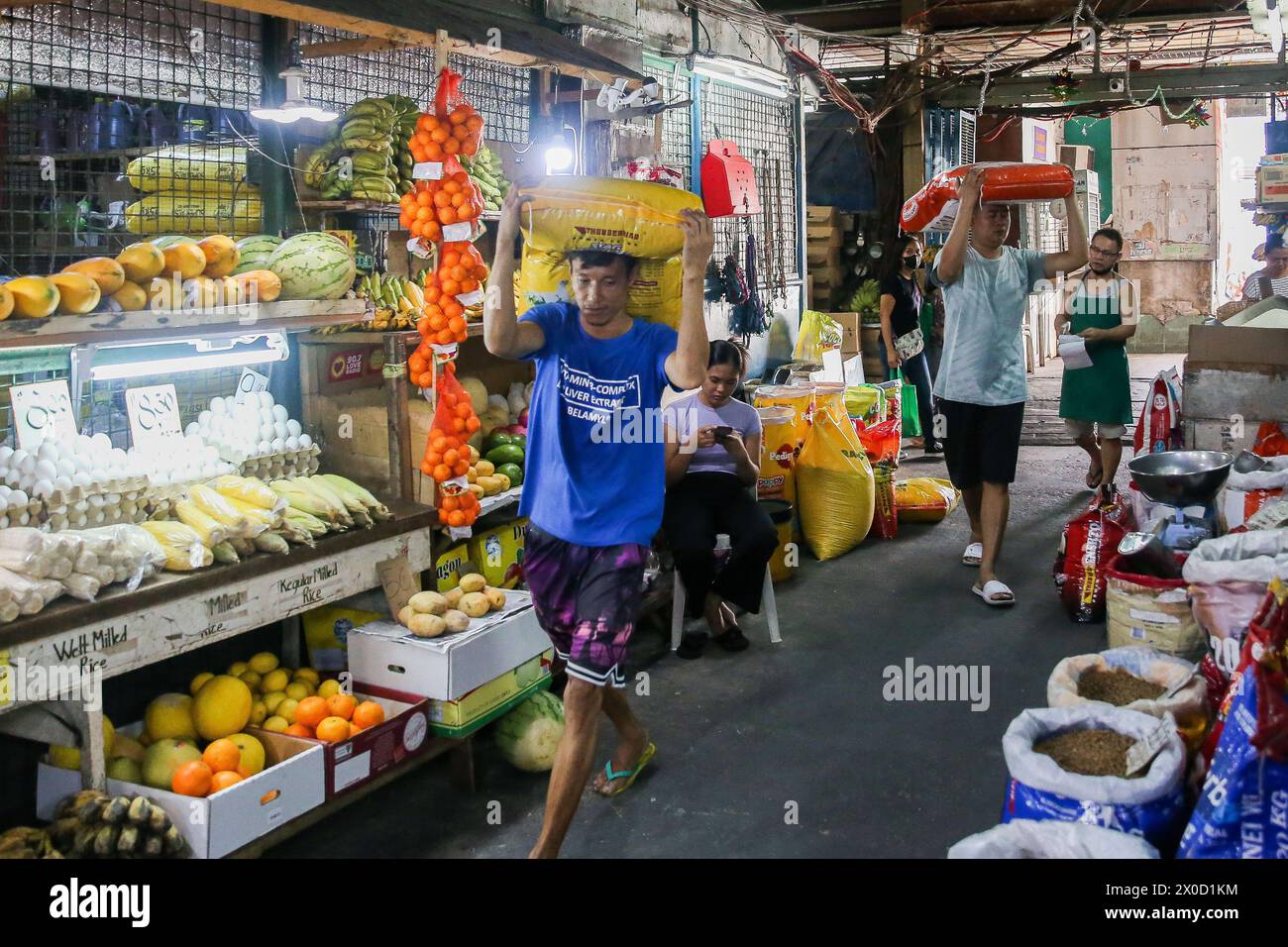 Quezon City, Philippinen. April 2024. Arbeiter tragen Säcke mit Tierfutter auf einem Markt in Quezon City, den Philippinen, am 11. April 2024. Die Wirtschaft Asiens und des Pazifiks ist nach wie vor stark, wobei die Wachstumsrate in den Entwicklungsländern der Region für 2024 und 2025 auf 4,9 Prozent prognostiziert wird, sagte die Asiatische Entwicklungsbank (ADB) Donnerstag in ihrem jüngsten Prognosebericht. Quelle: Rouelle Umali/Xinhua/Alamy Live News Stockfoto