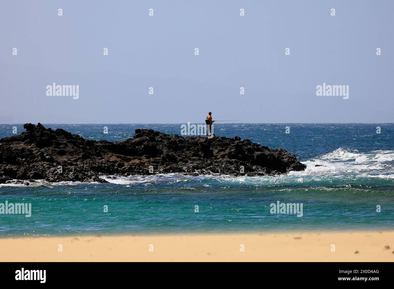 Mann fischt von einer kleinen felsigen Landzunge aus, El Cotillo, Fuerteventura. Vom Februar 2024 Stockfoto