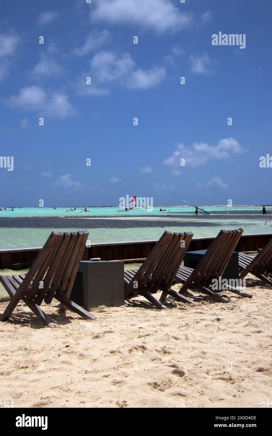 Liegestühle am Karibischen Strand mit Windsurfern in der Ferne, Sorobon Beach, Bonaire, Karibik Niederlande Stockfoto