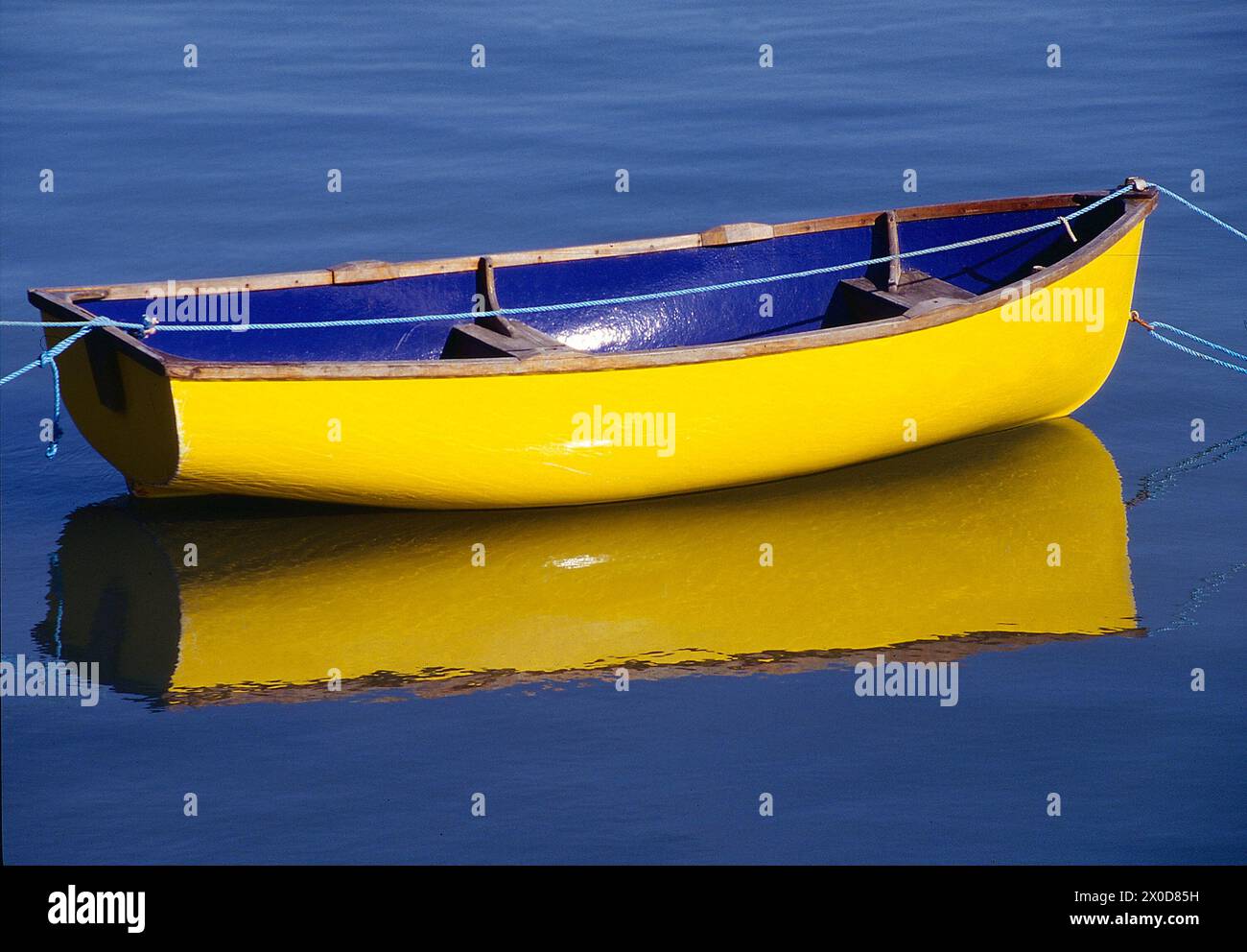 Gelbes hölzernes Ruderboot auf stillem Wasser mit Reflexion Stockfoto