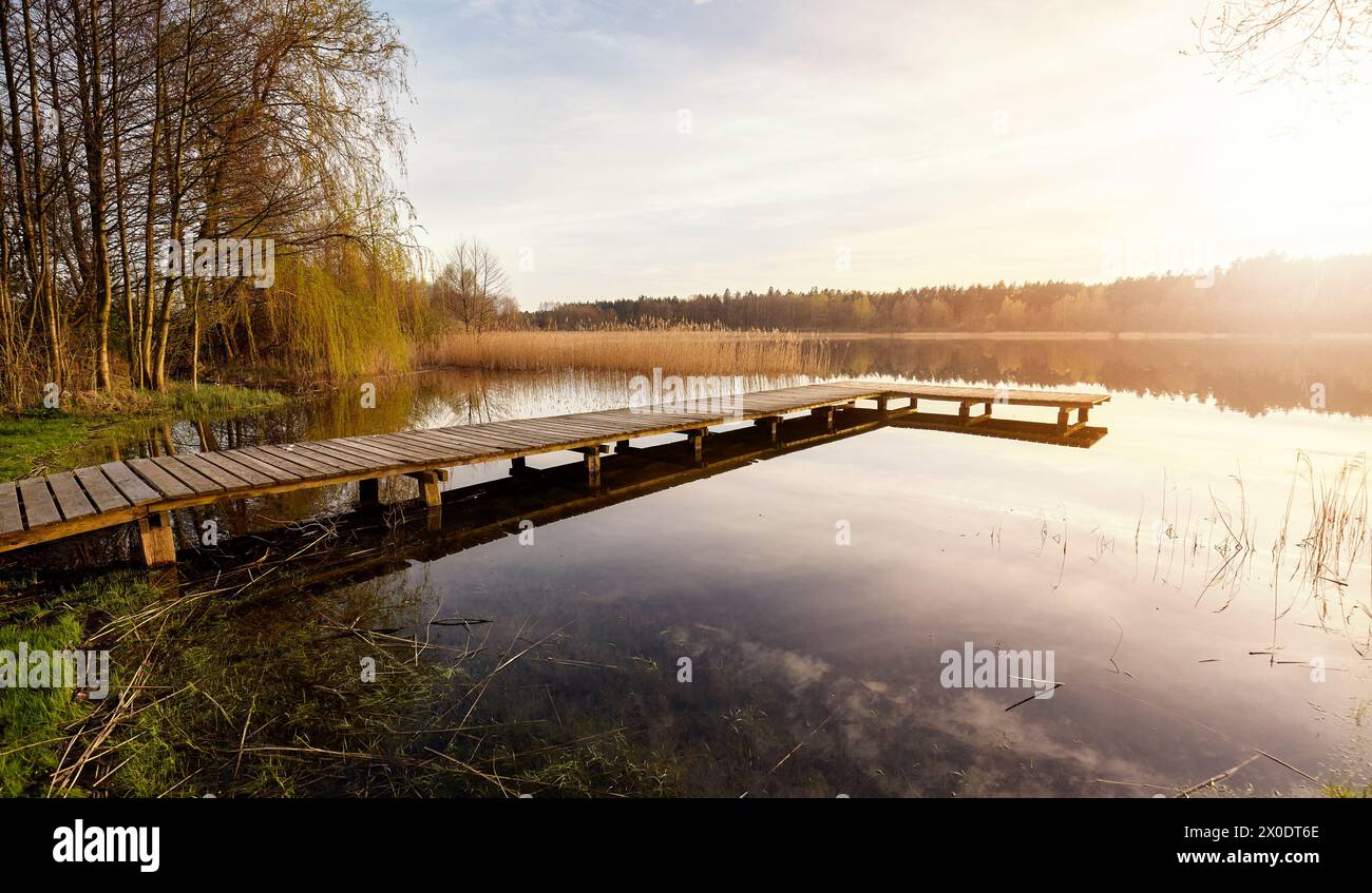 Malerischer Sonnenuntergang mit einem Pier auf einem See in der Nähe der Stadt Recz, Woiwodschaft Westpommern, Polen. Stockfoto
