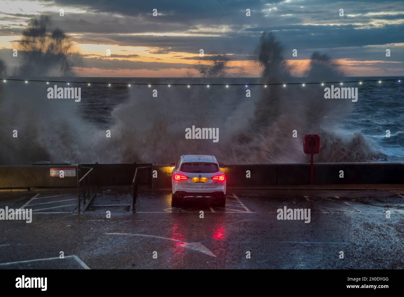 9. April 2024. Menschen im geparkten Auto beobachten, wie Wellen über der Promenade von Hunstanton in Norfolk während einer hohen Frühlingsflut brechen. Stockfoto