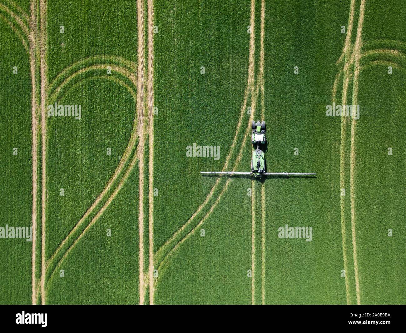 Rottweil, Deutschland. April 2024. Ein Landwirt fährt einen Traktor über ein Feld und sprüht Pestizide. (Luftaufnahme mit einer Drohne). Quelle: Silas Stein/dpa/Alamy Live News Stockfoto