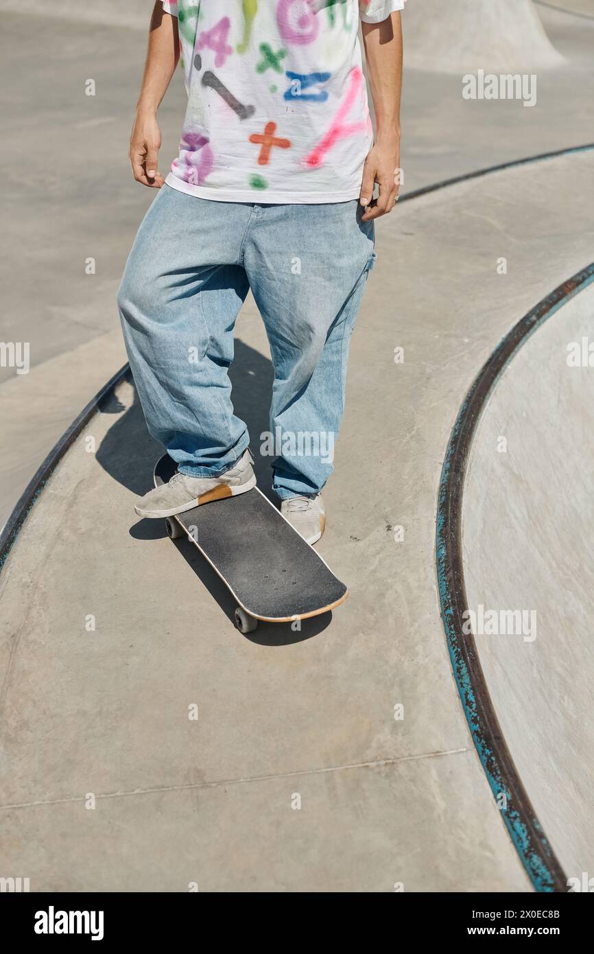 Ein junger Skater trotzt der Schwerkraft, während er an einem sonnigen Sommertag mit seinem Skateboard die Rampe in einem Skatepark hinauf fährt. Stockfoto