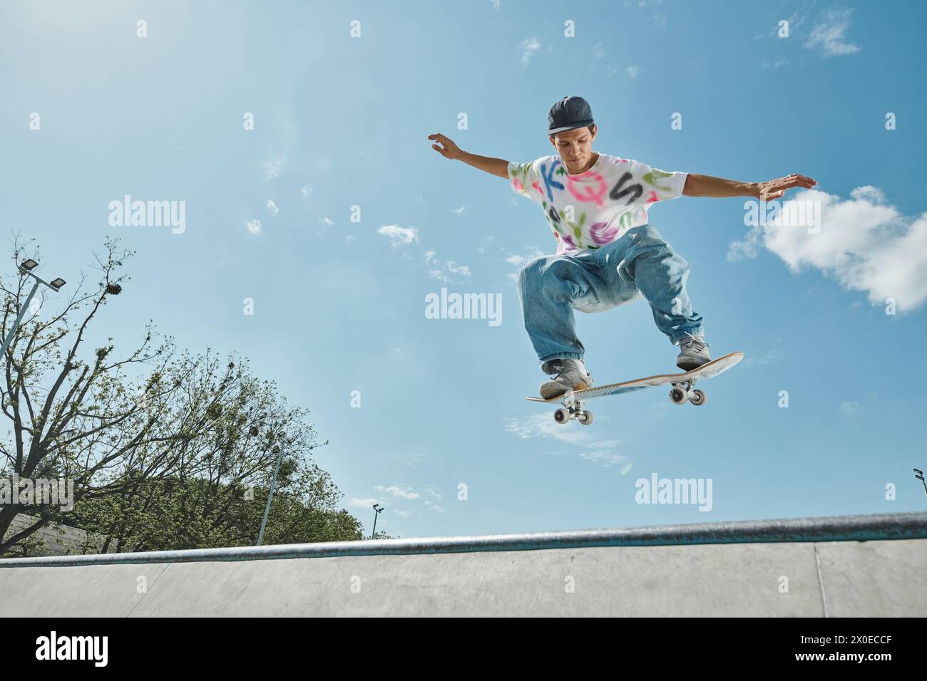 Ein junger Skater trotzt der Schwerkraft und schwingt auf seinem Skateboard in einem sonnigen Skatepark durch die Luft. Stockfoto