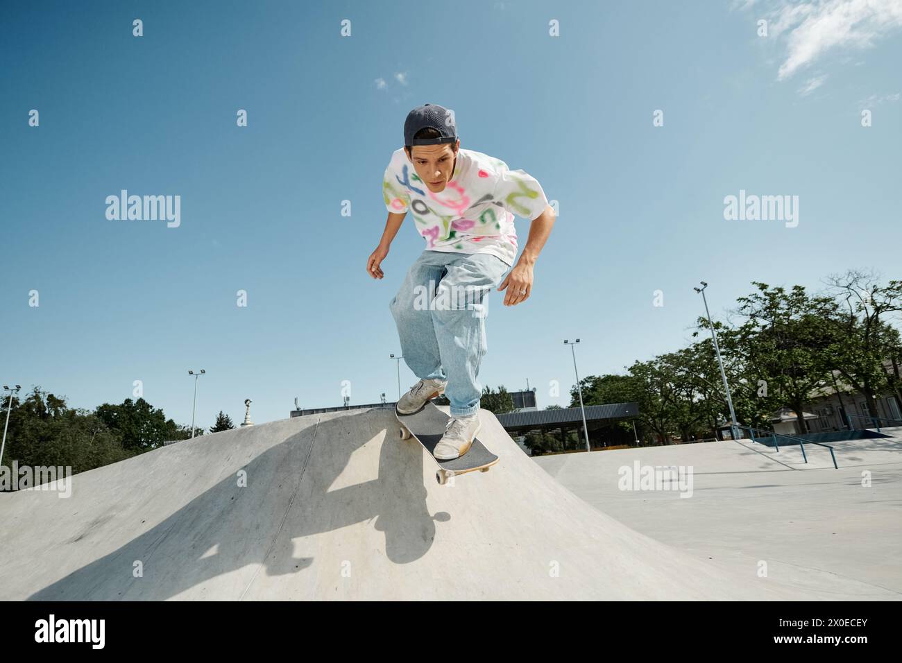 Ein junger Skater-Junge, der einen beeindruckenden Skateboardtrick entlang einer Rampe in einem sonnigen Skatepark im Freien vorführt. Stockfoto