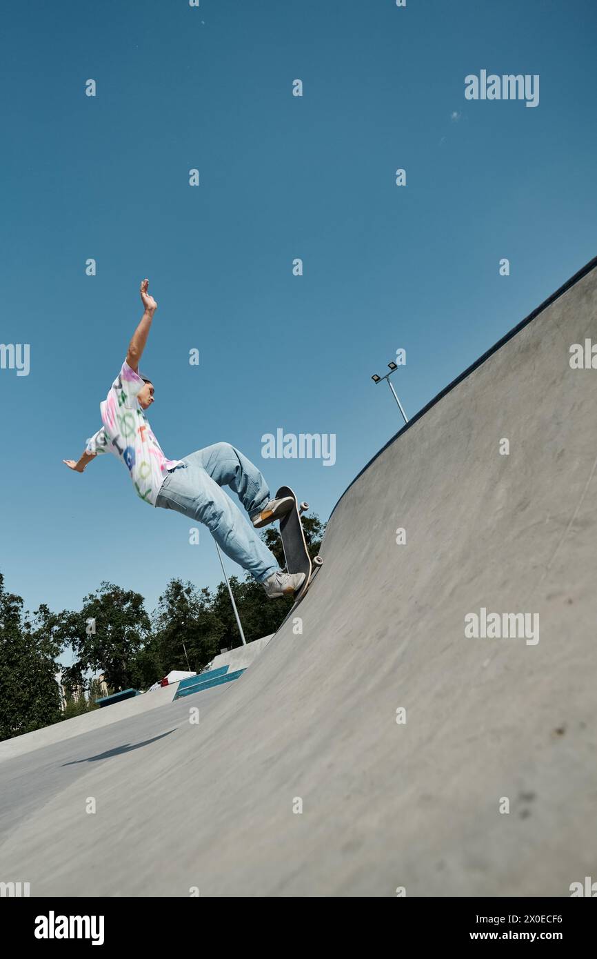 Ein junger Skater trotzt der Schwerkraft, während er in einem sonnigen Skatepark mit seinem Skateboard die Seite einer Rampe hinauf fährt. Stockfoto