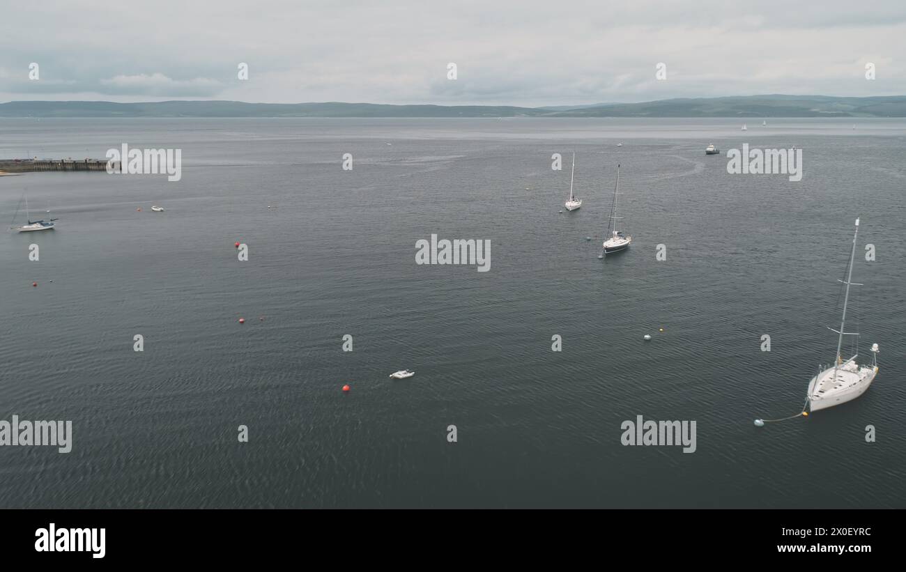 Yachten, Segelboote, Schiffe an der Meeresbucht. Schottisch Niemand Naturlandschaft am Sommertag. Wassertransport im Seehafen von Arran Island, Schottland, Vereinigtes Königreich. Bootstour im Kino Stockfoto