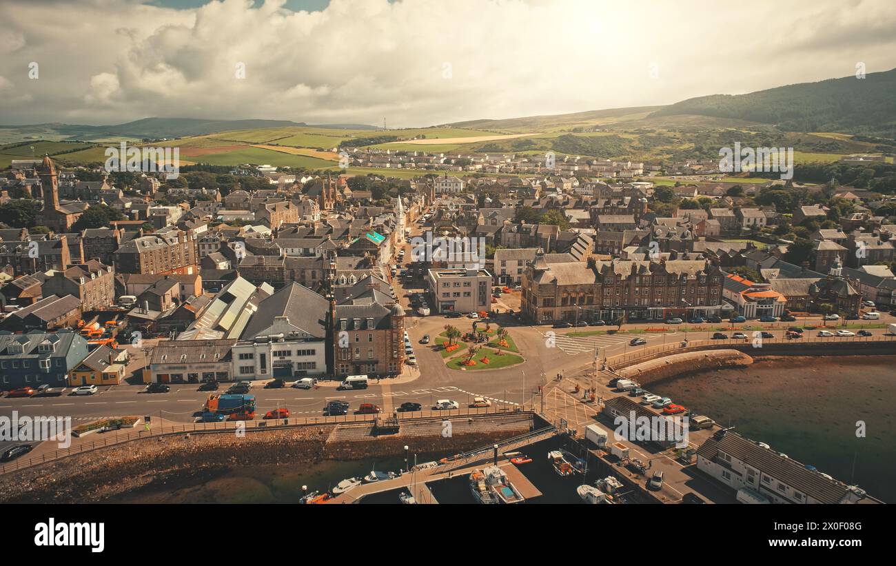 Harbor Sun City City aus der Vogelperspektive. Seeblick mit Yachten, Schiffen in den Straßen der Innenstadt, Autobahn. Verkehrsstraße an modernen Gebäuden. Autos fahren am Meer. Campbeltown, Schottland, Europa auf Rise Up Shot Stockfoto