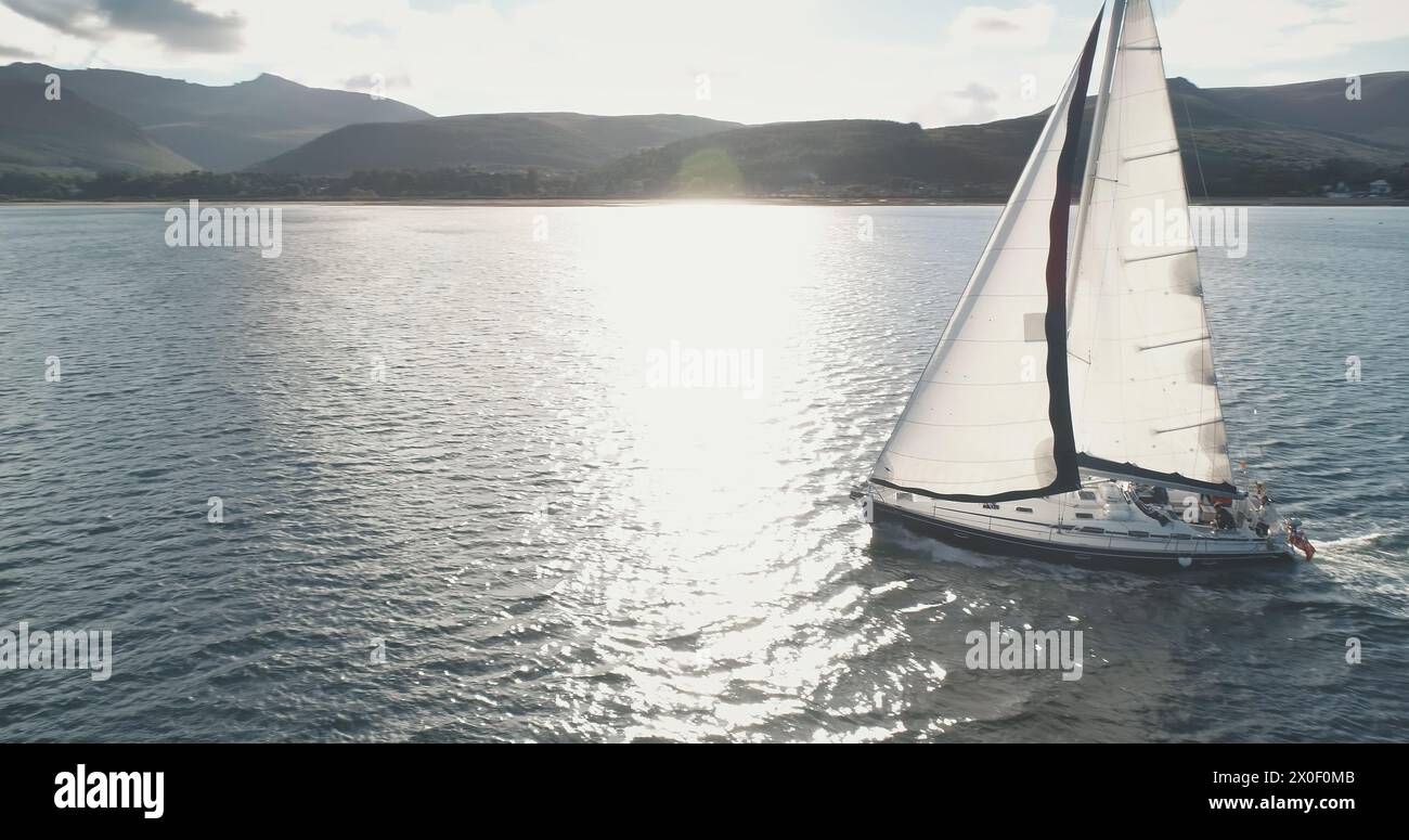 Segelboot Yachting am offenen Hafen mit Sonnenspiegelantenne. Nahaufnahme der Yachtfahrt mit Passagieren. Episches Segelboot auf dem Meer mit Tour durch Reisende. Sommerurlaub auf einem Segelboot in Schottland, Europa Stockfoto