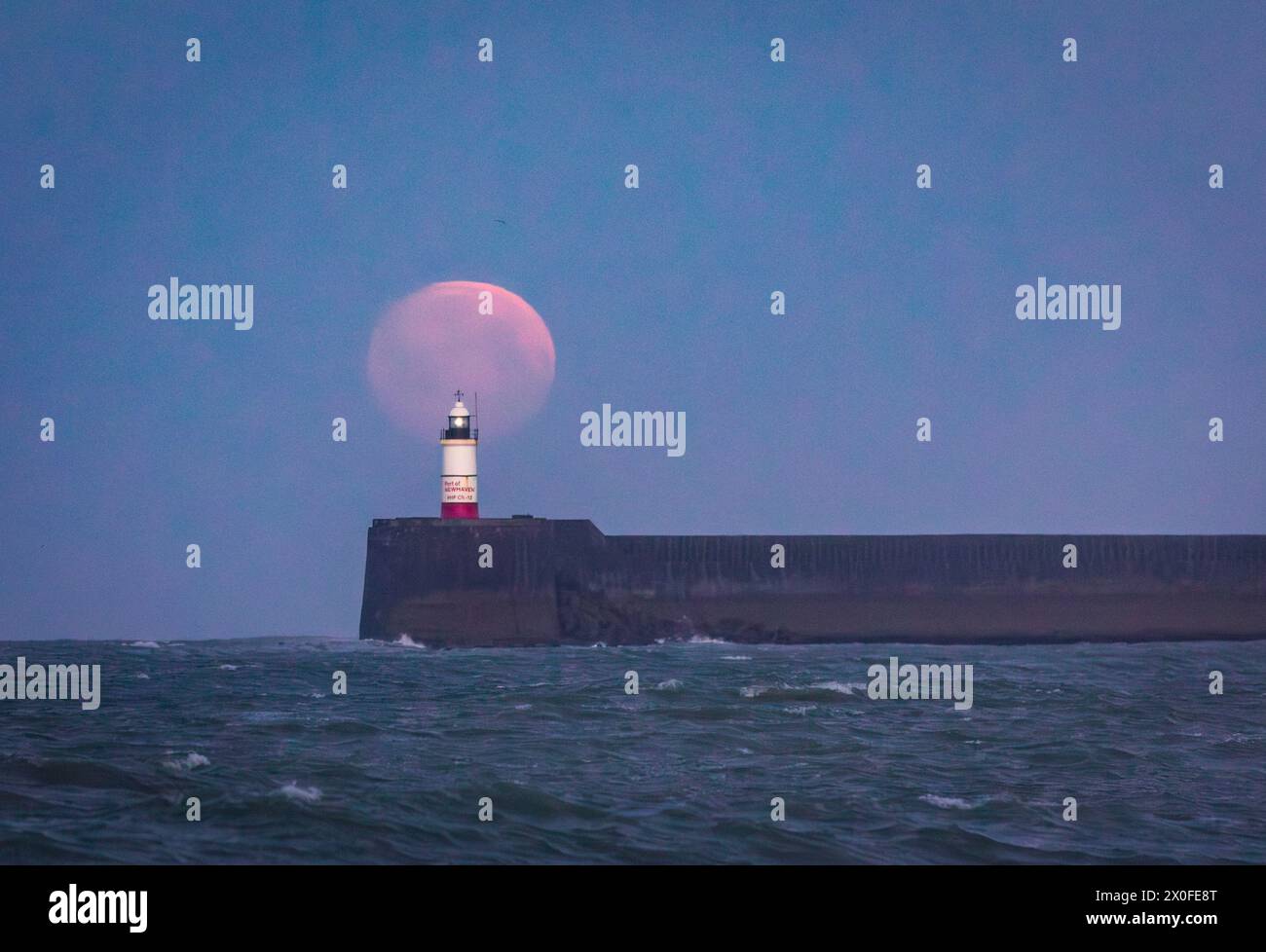 Vollmonduntergang im März hinter dem Leuchtturm Newhaven vom Seaford Beach an der Ostküste von Sussex im Südosten Englands Großbritannien Stockfoto