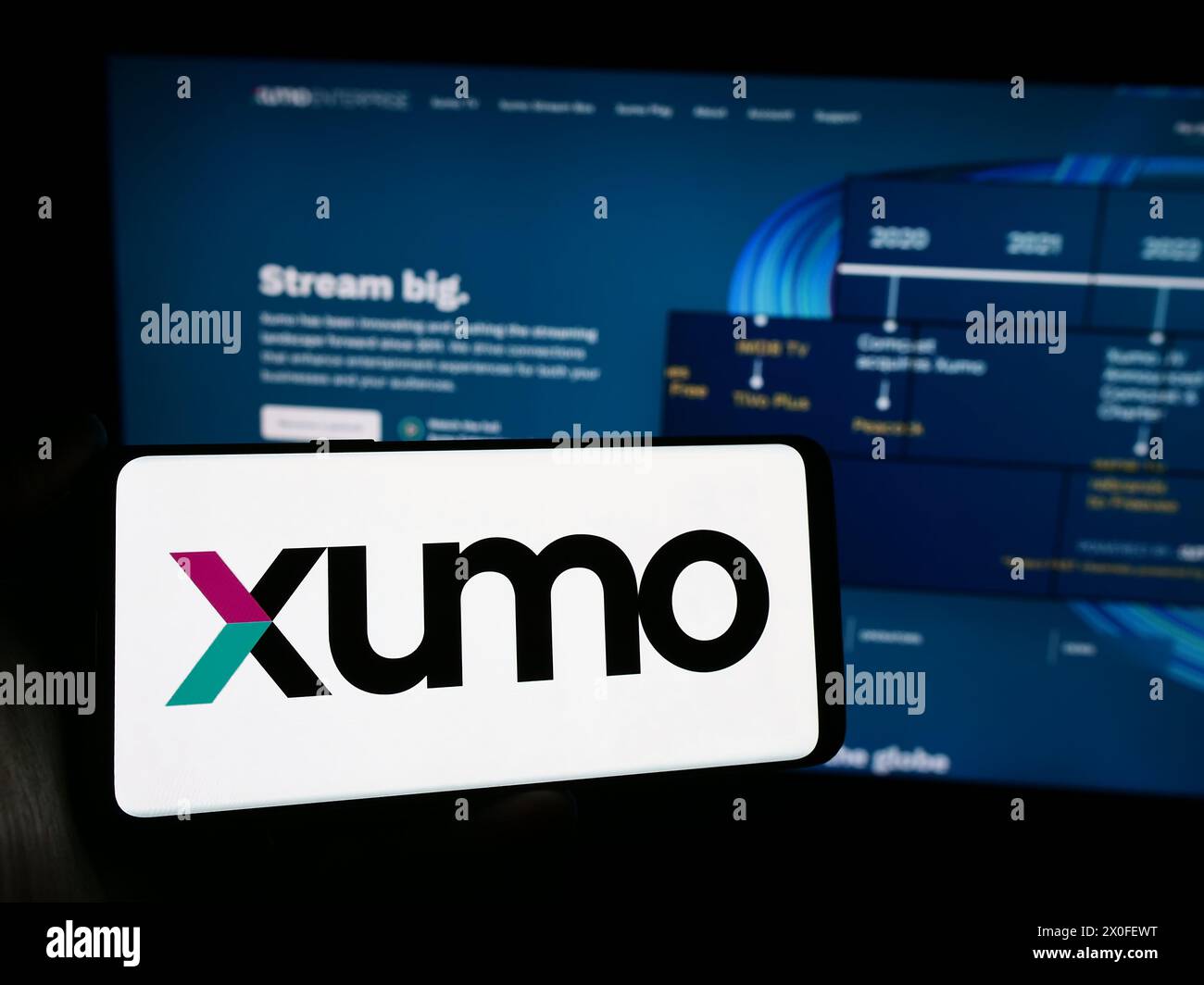 Person, die ein Mobiltelefon mit dem Logo des US-amerikanischen Video- und Fernsehstreaming-Unternehmens Xumo LLC vor der Business-Website hält. Schwerpunkt auf dem Display des Telefons. Stockfoto