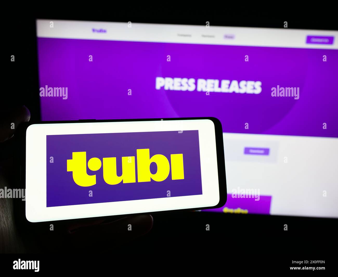 Person, die ein Smartphone mit dem Logo der US-Streaming-Plattform Tubi Inc. Vor der Website hält. Schwerpunkt auf dem Display des Telefons. Stockfoto