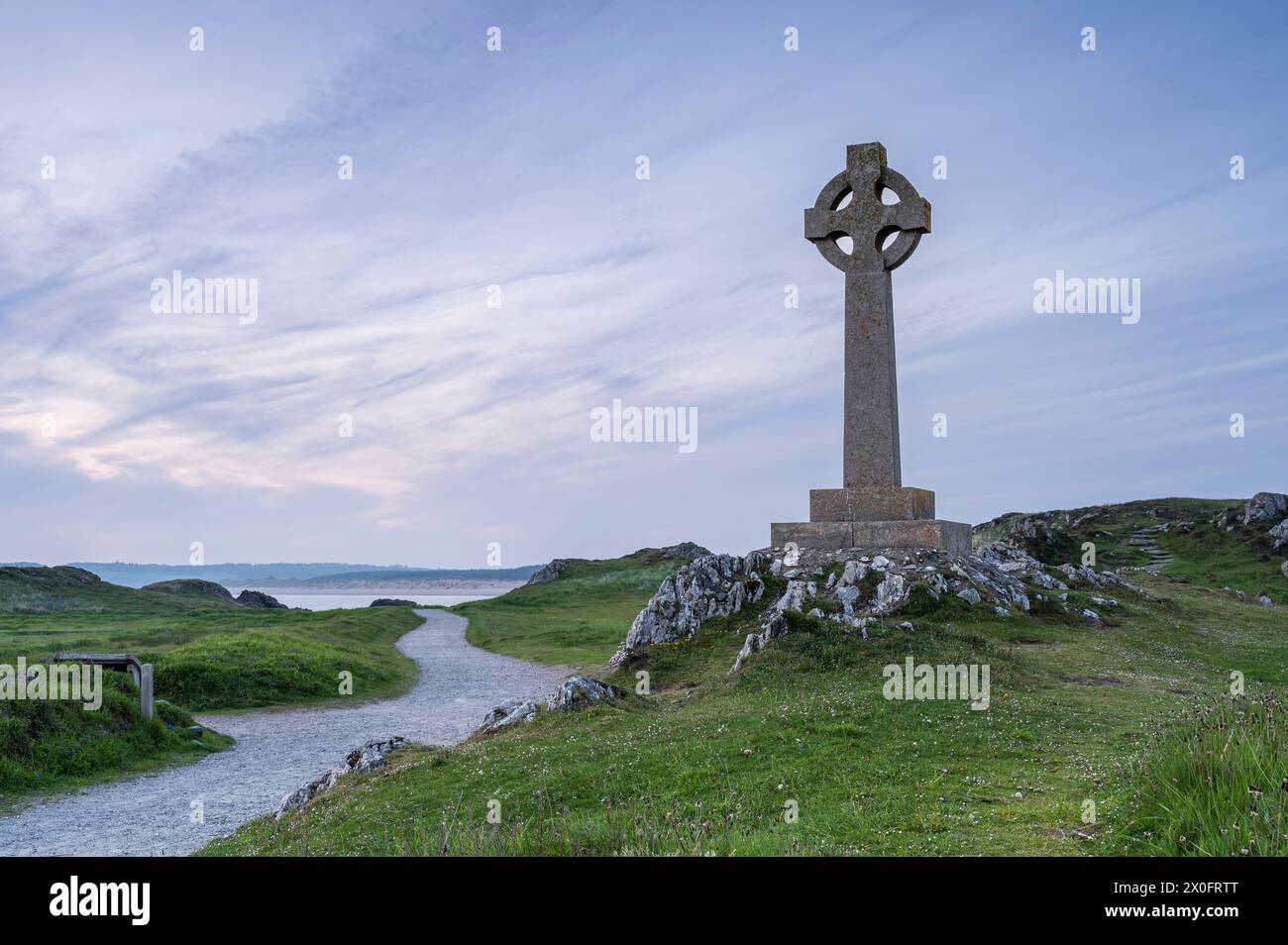 Ein keltisches Kreuz auf Llanddwyn, entlang der Küste von Anglesey, Wales, in der Nähe von Newborough Beach. Es ist Sonnenuntergang Stockfoto