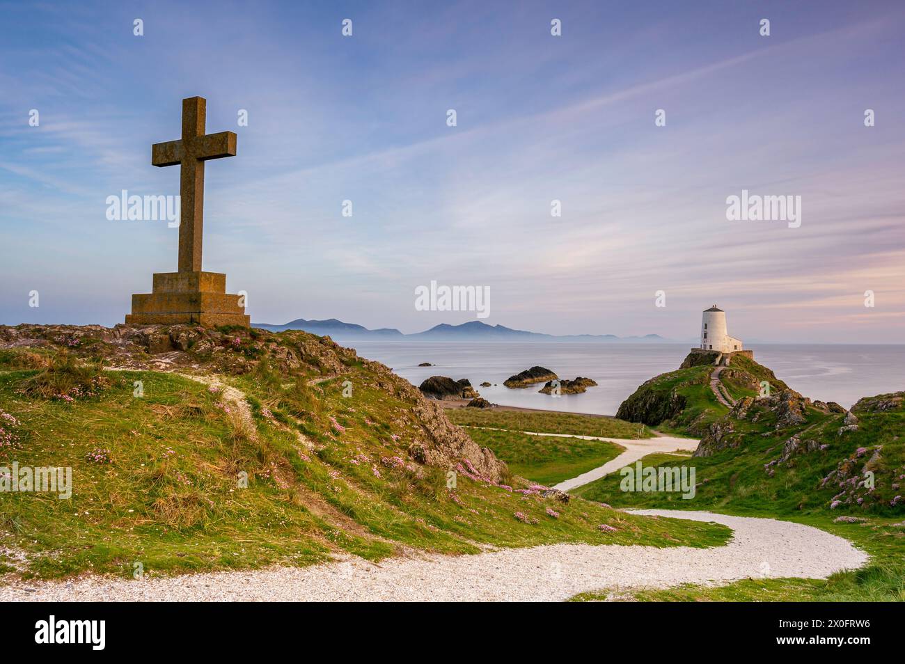 Ynys Llanddwyn Lighthouse und ein religes Kreuz, bei Sonnenuntergang an einem Sommertag. Nordwales, Anglesey Stockfoto