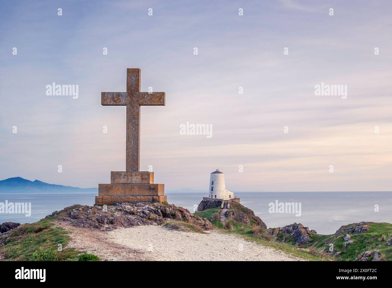 Ynys Llanddwyn Lighthouse und ein religes Kreuz, bei Sonnenuntergang an einem Sommertag. Nordwales, Anglesey Stockfoto