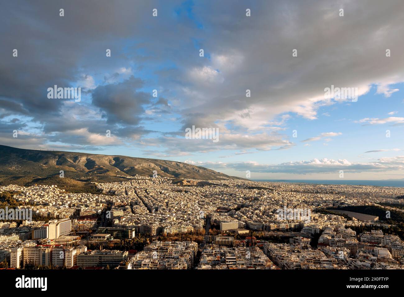 Majestätischer Sonnenuntergang mit herrlichen Wolken über dem Hymettus-Berg und der Stadt Athen, Griechenland. Es gibt mehrere Stadtteile wie Ilioupoli, Pagkrati, Ili Stockfoto