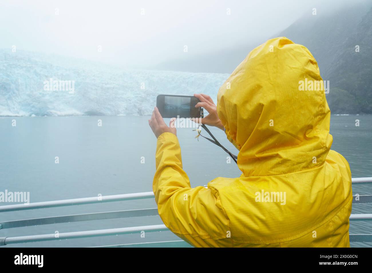 Tourist macht Smartphone-Fotos vom Holgate-Gletscher im Regen. Kenai Fjords National Park, Seward, Alaska. Stockfoto