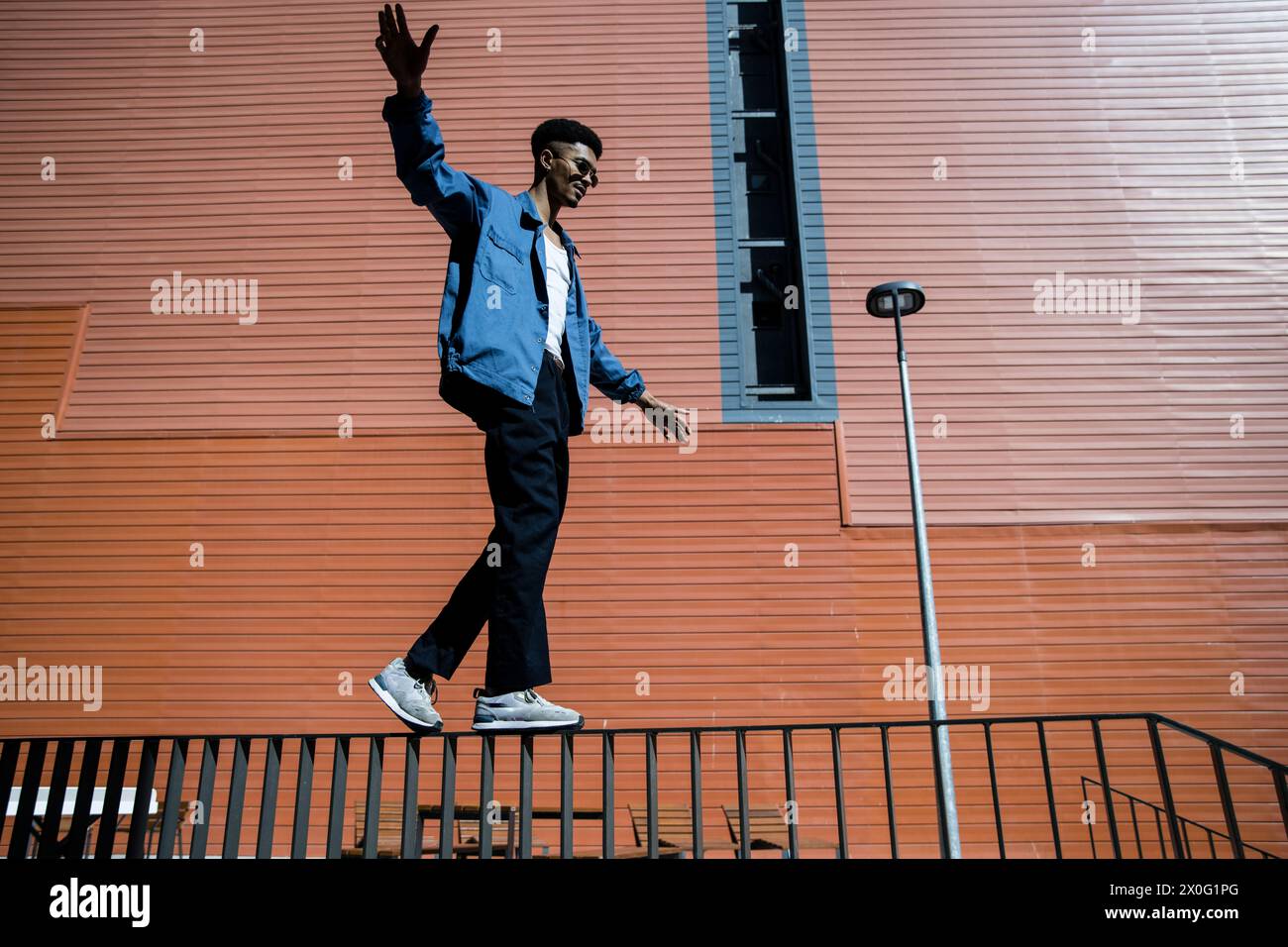 Fokussierter trendiger Mann, der auf einem Handlauf balanciert. Stockfoto