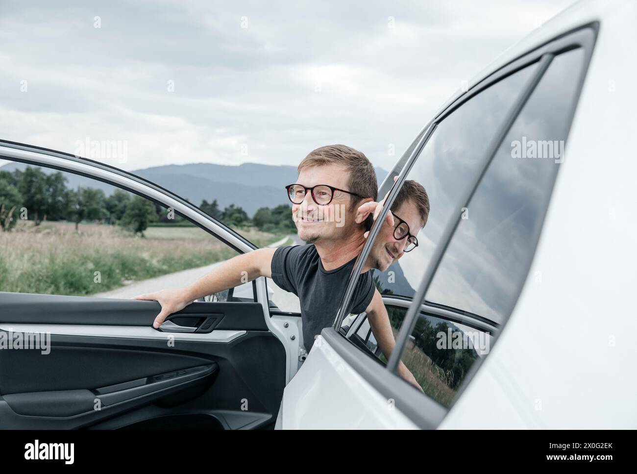 Fröhlicher Mann, der im Auto sitzt und mit einem dankbaren Ausdruck aufblickt Stockfoto