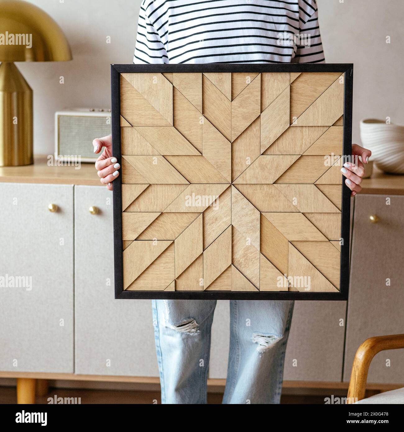 Ein Mädchen hält ein handgefertigtes Holzgemälde in den Händen Stockfoto