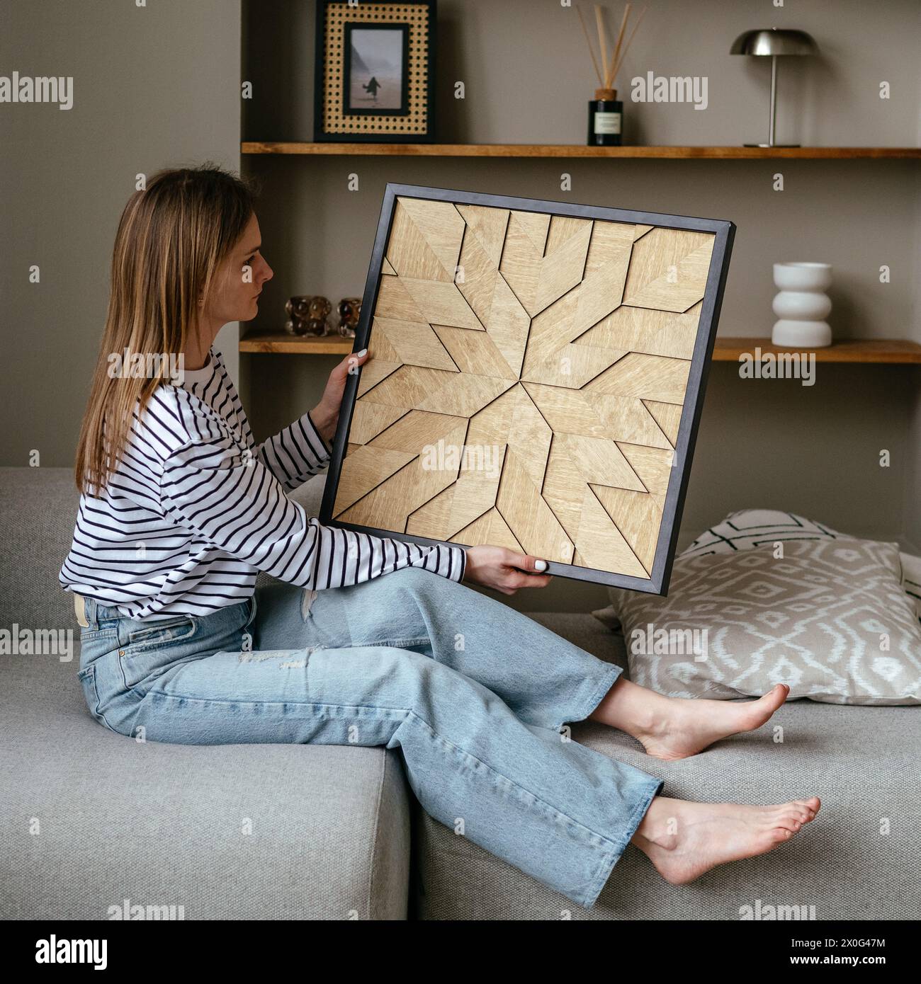 Ein Mädchen hält ein handgefertigtes Holzgemälde in den Händen Stockfoto