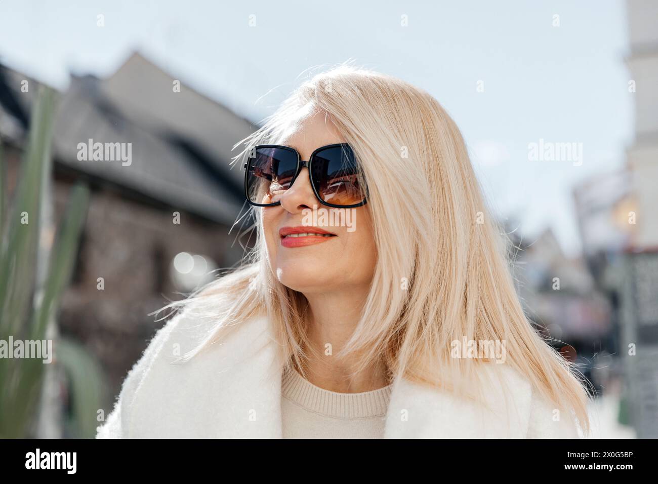 Reife Frau mit blonden Haaren, die Sonnenbrille an einem sonnigen Tag trägt Stockfoto