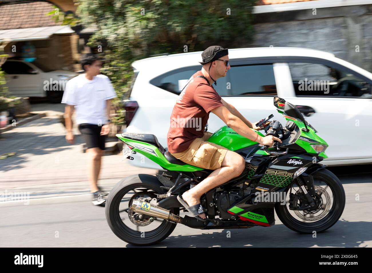 Touristen, die auf Bali ein großes Motorrad ohne Helm fahren Stockfoto