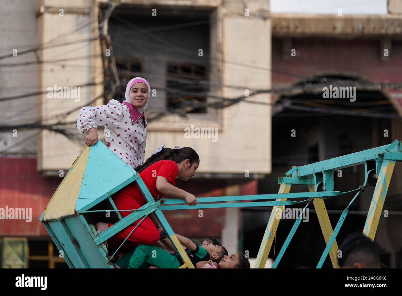 Mossul, Irak. April 2024. Irakische Kinder spielen auf einer Schaukel in einem mobilen Vergnügungspark, während sie Eid al-Fitr feiern, das das Ende des muslimischen Fastenmonats Ramadan in der Altstadt von Mosul, Nordirak Credit: SOPA Images Limited/Alamy Live News Stockfoto