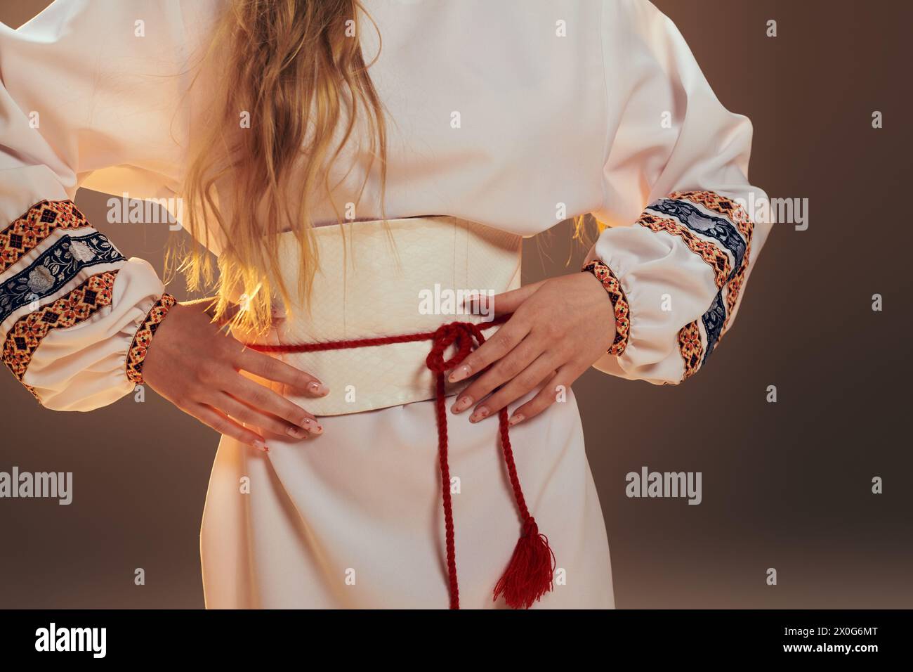 Eine junge Frau in einem traditionellen weißen Kleid mit langen Haaren, die eine ätherische und märchenhafte Präsenz in einem Studio ausstrahlt. Stockfoto