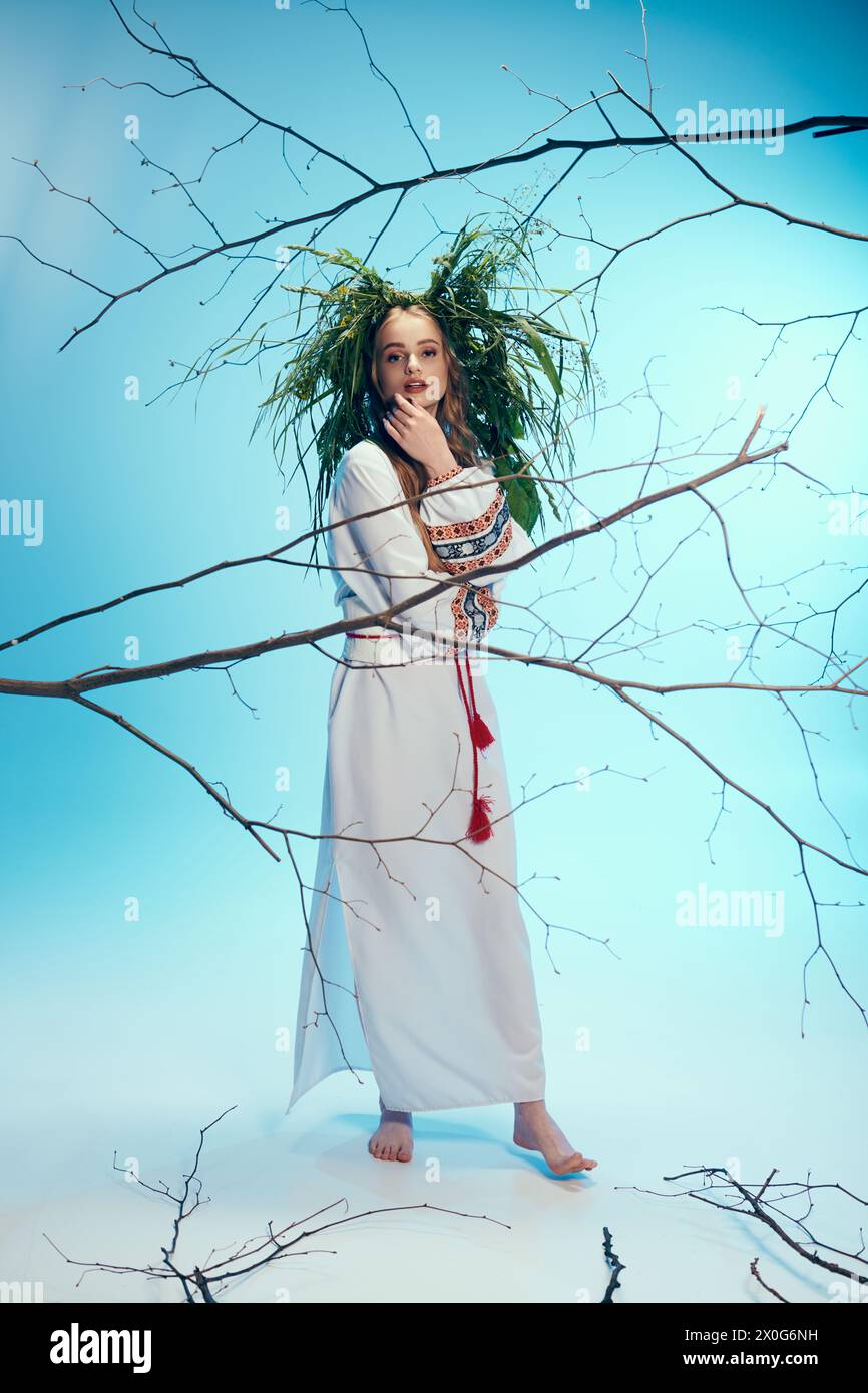 Eine junge Frau in einem weißen Kleid steht anmutig vor einem majestätischen Baum und strahlt eine ätherische Atmosphäre aus. Stockfoto