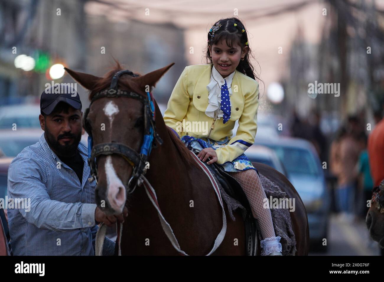 Mossul, Irak. April 2024. Irakische Mädchen reiten in einem mobilen Vergnügungspark zu Pferd, während sie Eid al-Fitr feiern, das das Ende des heiligen muslimischen Fastenmonats Ramadan in der Altstadt von Mosul, Nordirak Credit: SOPA Images Limited/Alamy Live News Stockfoto