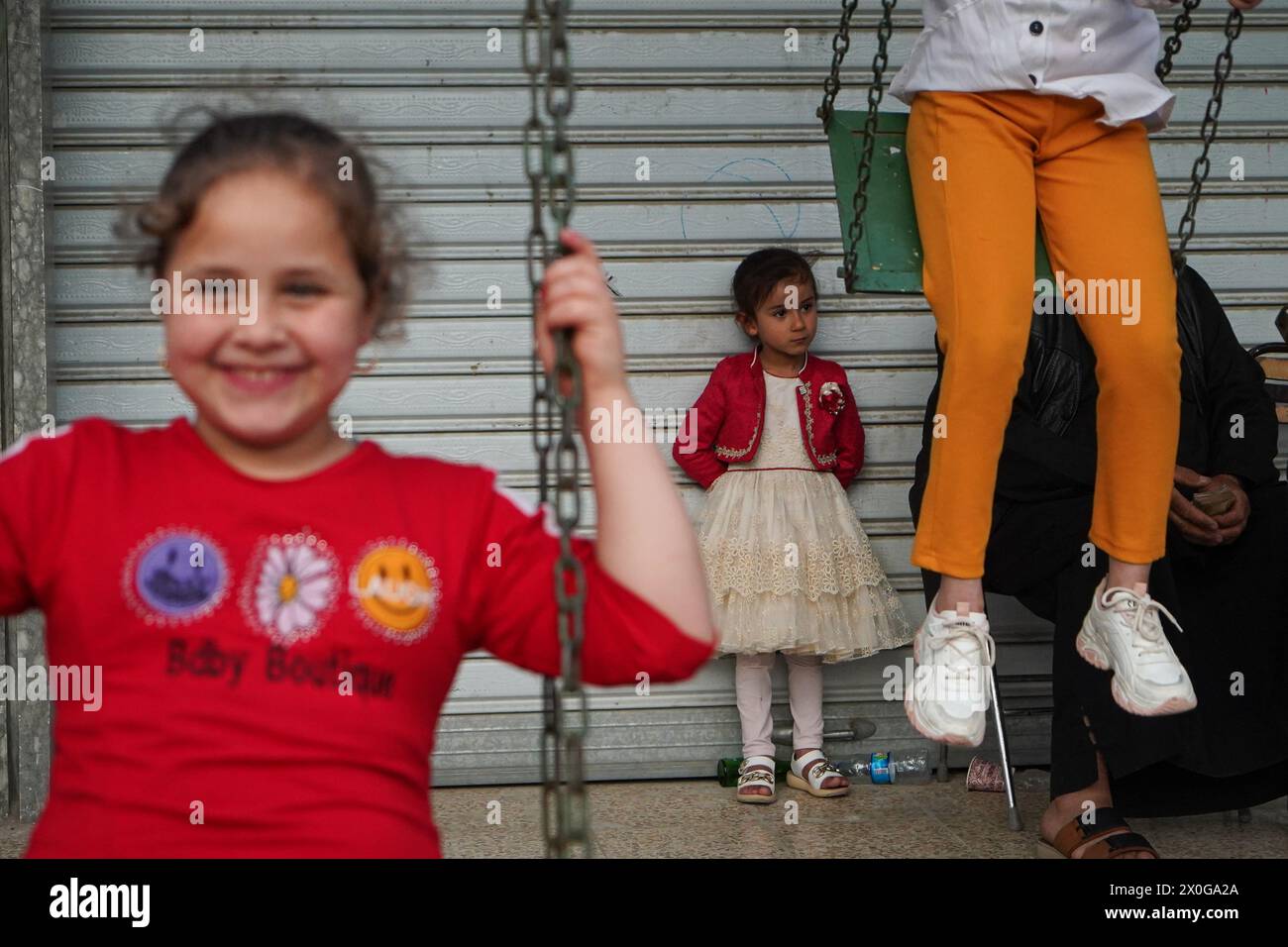 Mossul, Irak. April 2024. Irakische Kinder spielen auf einer Schaukel in einem mobilen Vergnügungspark, während sie Eid al-Fitr feiern, der das Ende des muslimischen Fastenmonats Ramadan in der Altstadt von Mosul im Nordirak markiert (Foto: Ismael Adnan/SOPA Images/SIPA USA) Credit: SIPA USA/Alamy Live News Stockfoto