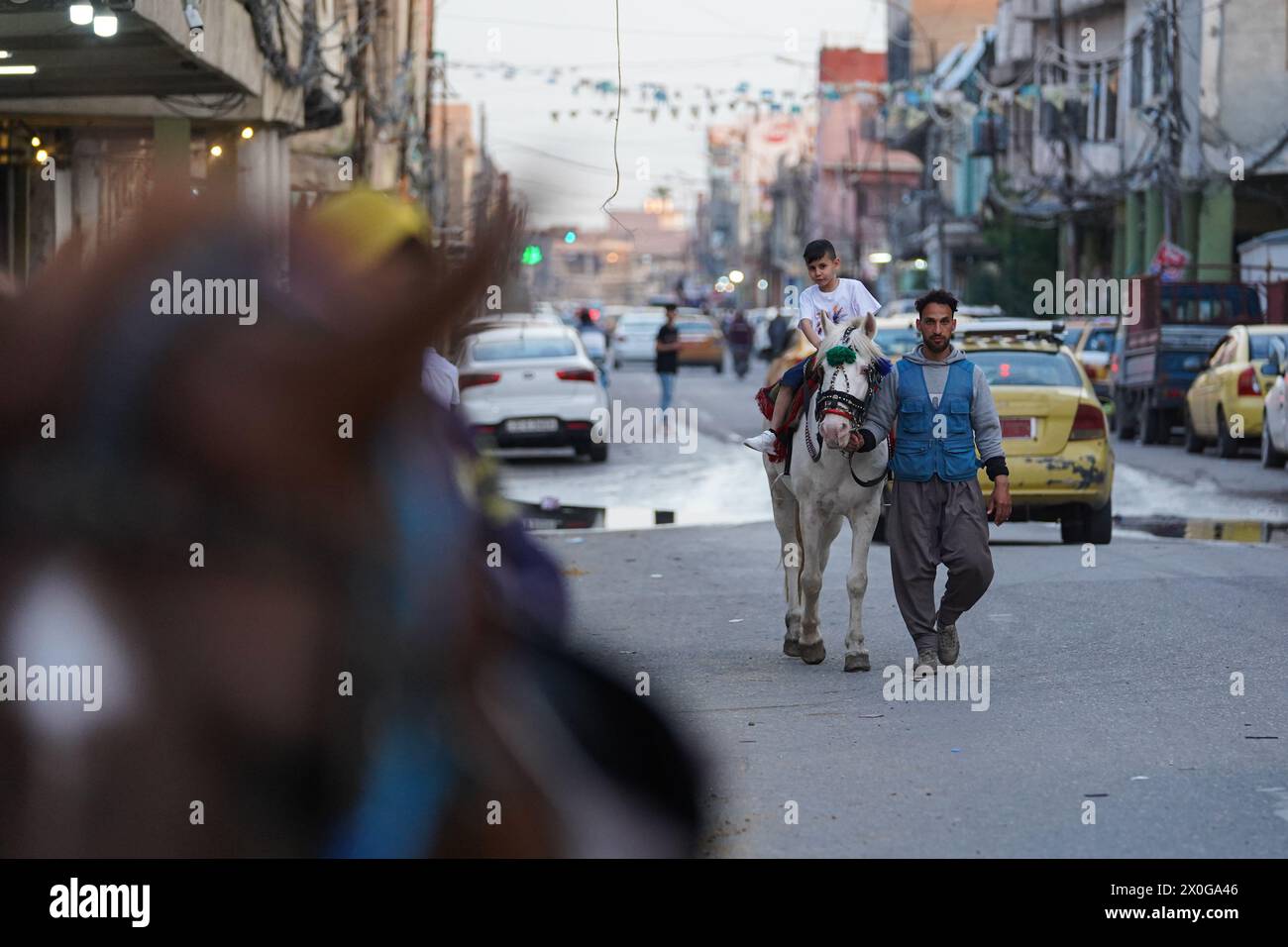 Mossul, Irak. April 2024. Der irakische Junge reitet in einem mobilen Vergnügungspark zu Pferd, während er Eid al-Fitr feiert, der das Ende des muslimischen Fastenmonats Ramadan in der Altstadt von Mosul im Nordirak markiert (Foto: Ismael Adnan/SOPA Images/SIPA USA) Credit: SIPA USA/Alamy Live News Stockfoto