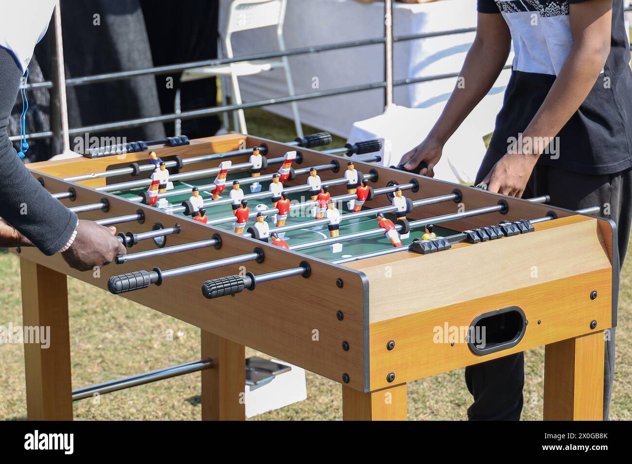 Zugeschnittenes Bild eines Jungen und eines jungen Mannes, die Tischkicker spielen, während sie sich im Freien entspannen Stockfoto