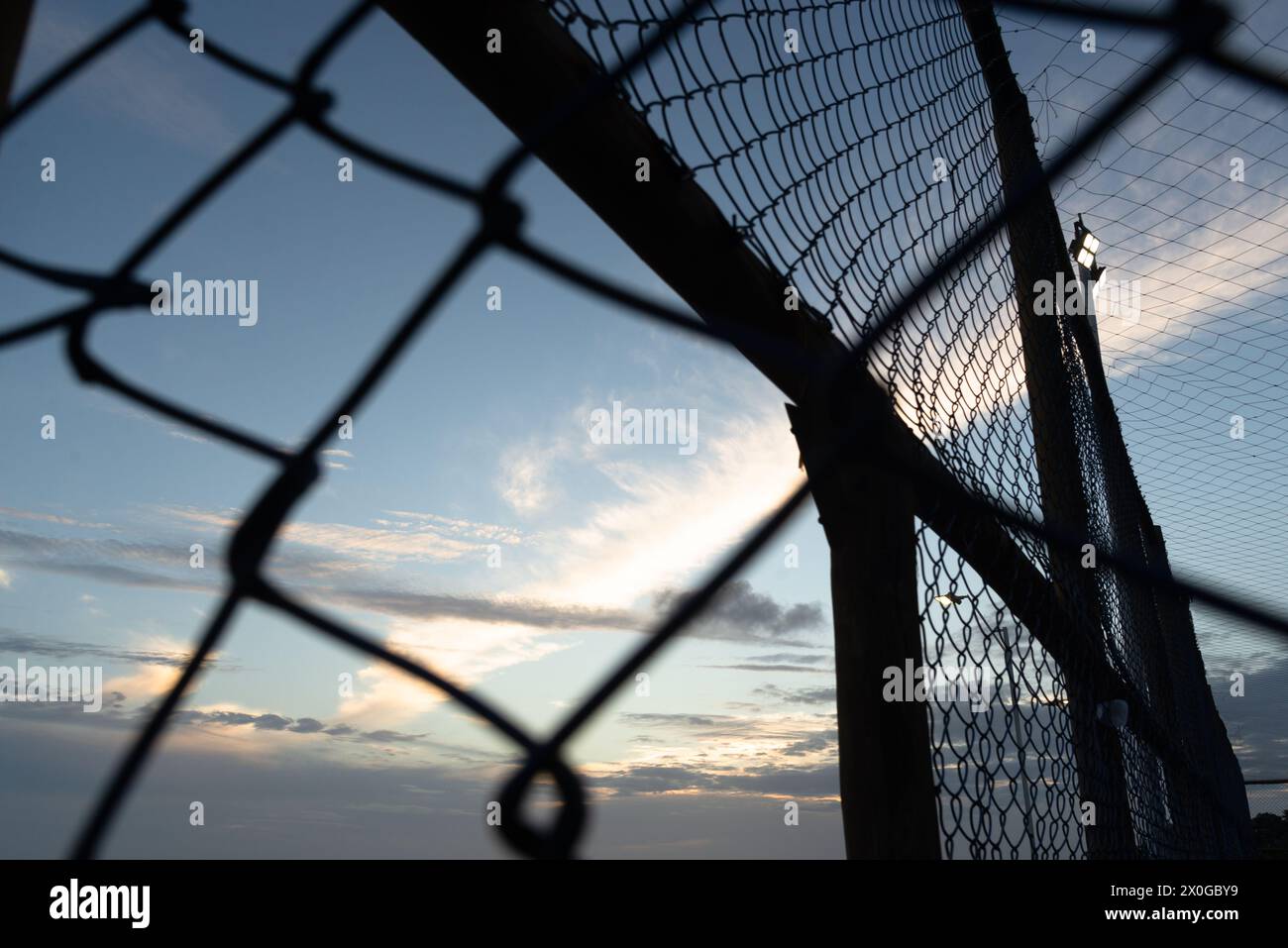 Netz und Zaun eines alten verlassenen Sportplatzes gegen Sonnenuntergang. Sportausrüstung. Stockfoto