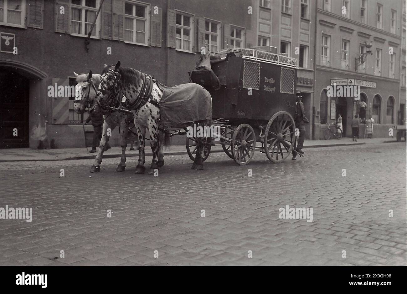 Vor dem Hotel Goggl in Landsberg steht eine von 2 weißen Pferden gezogene Postkutsche [automatisierte Übersetzung] Stockfoto