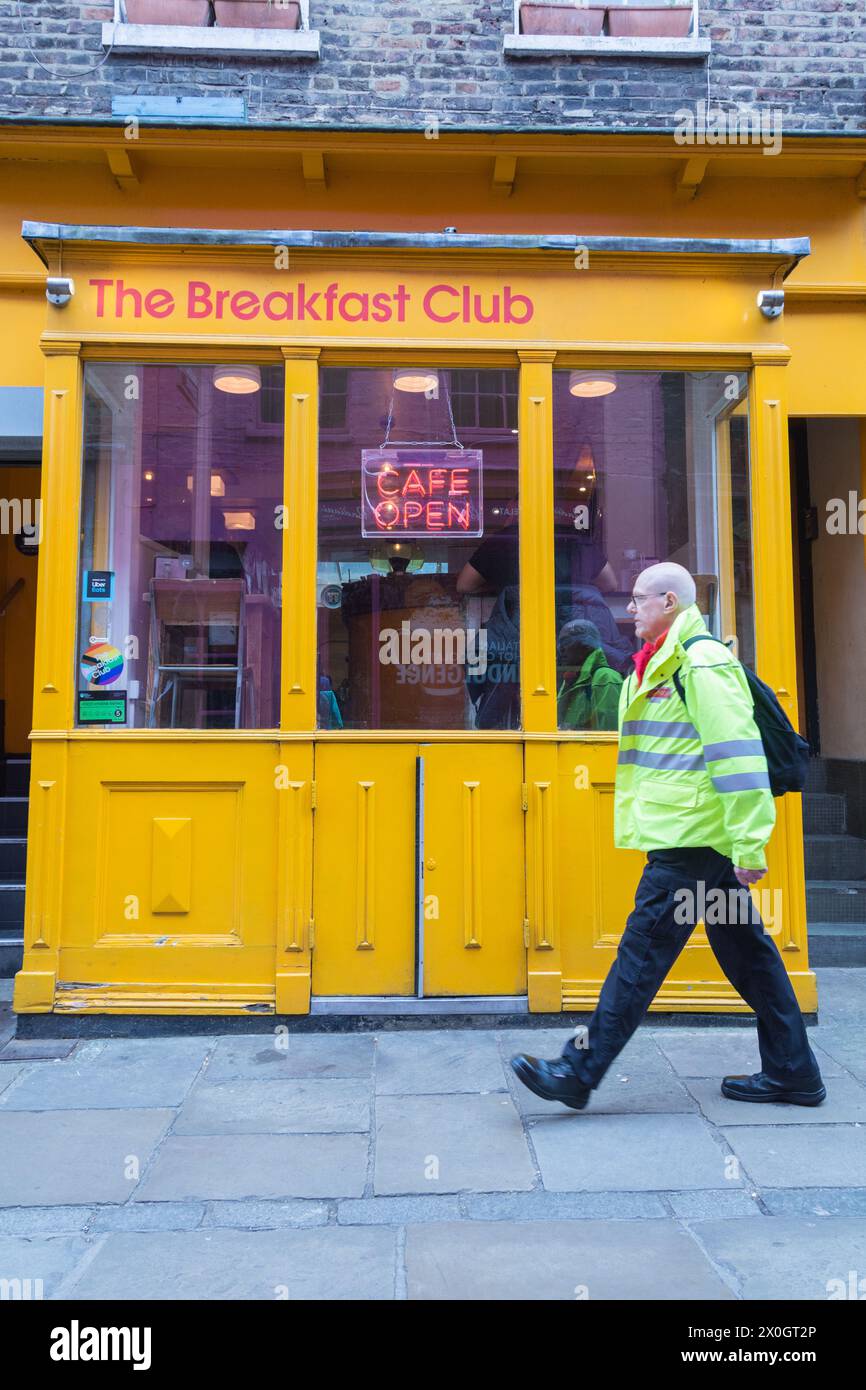 Ein Mann in einer hochsichtbaren Jacke, der vor dem Breakfast Club Angel, Camden Passage, Islington, London, N1, läuft. England, Großbritannien Stockfoto