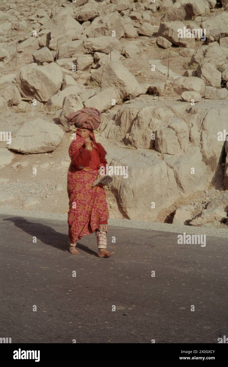 Eine Frau eines persischen Bauern mit roter Robe und Turban auf einer Straße vor Schreien in Bisotun. [Automatisierte Übersetzung] Stockfoto