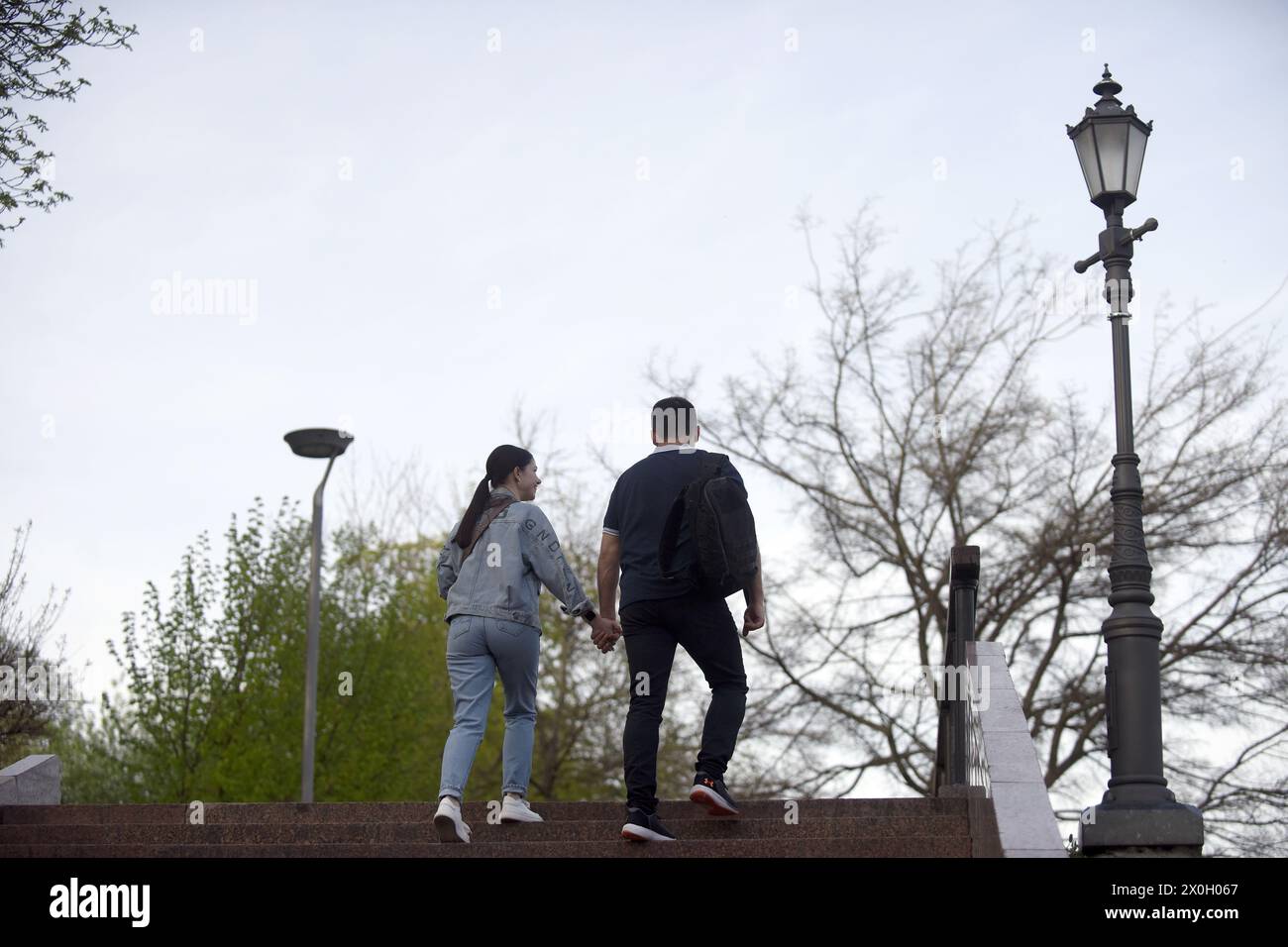 Nicht exklusiv: KIEW, UKRAINE - 11. APRIL 2024 - Ein Mann und eine Frau gehen Hand in Hand die Treppen im Bergpark Volodymyrska, Kiew, Hauptstadt der Ukraine. Stockfoto