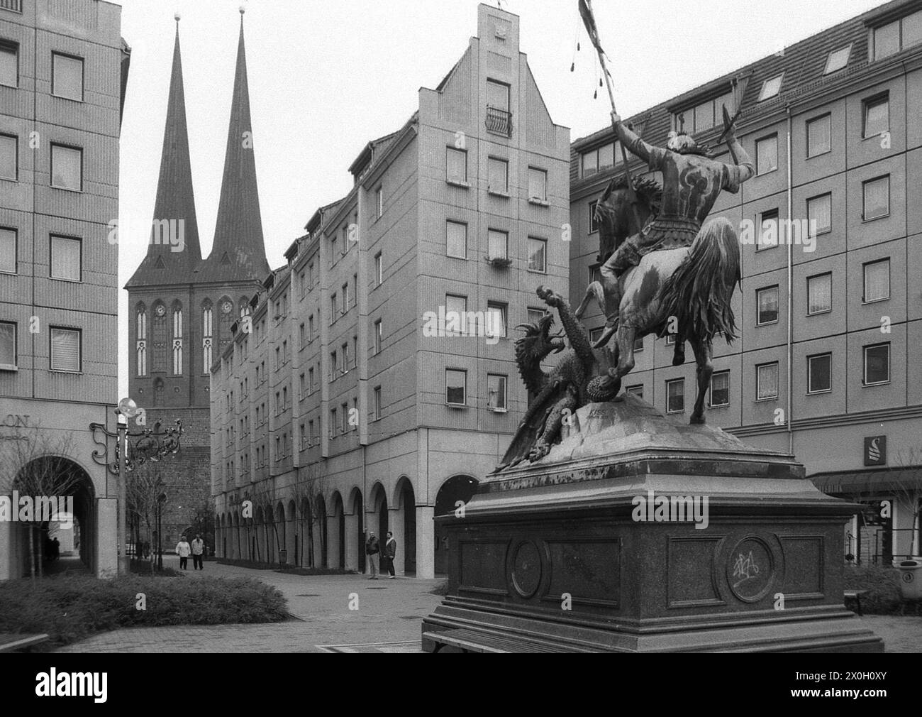 Bronzeskulptur des Heiligen Georg im Kampf gegen den Drachen im Nikolaiviertel in Berlin. Links sind die Zwillingstürme der St. Nikolaikirche. Stockfoto